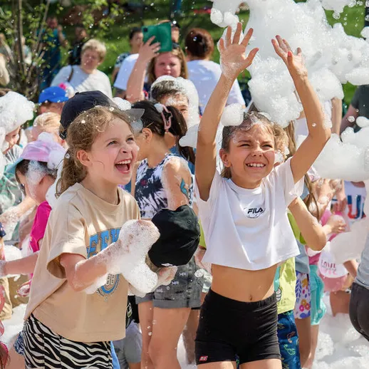 Дети наслаждаются игрой с мыльными пузырями на летнем празднике в парке