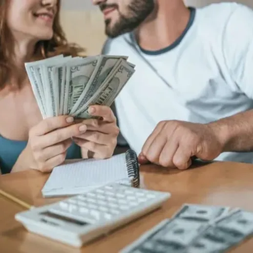 Молодая пара считает деньги за столом в уютной комнате, наслаждаясь приятным моментом совместной работы