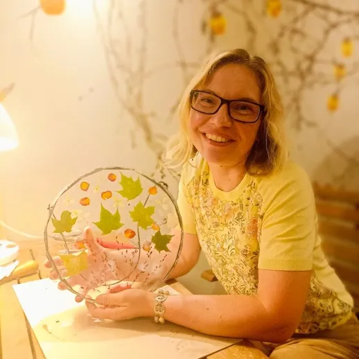 Женщина создает осенний декор из листьев и фруктиков в уютной комнате с теплым светом