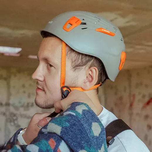 Мужчина в защитном шлеме надевает альпинистское снаряжение в заброшенном здании