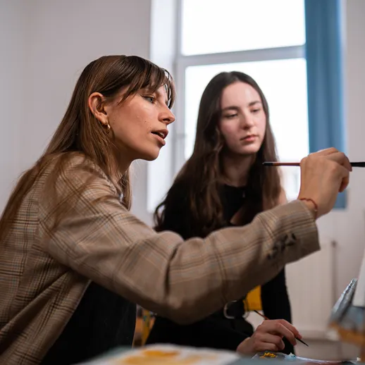 Учитель и ученица занимаются рисованием в уютной студии на солнечном дне