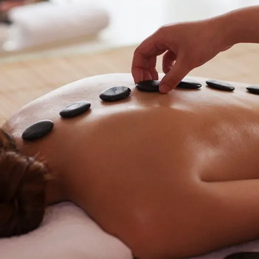 Расслабляющий массаж с горячими камнями в спа-центре на фоне уютной обстановки и натуральных материалов