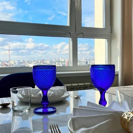 Столовая обстановка с синими бокалами и видом на город в ясный день