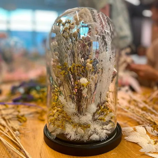 Сухие цветы в стеклянном куполе на столе в мастерской в осеннее время
