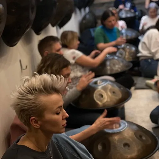 Занятие по игре на хангах в уютной студии, наполненной музыкой и гармонией, с участниками разных возрастов и уровней мастерства