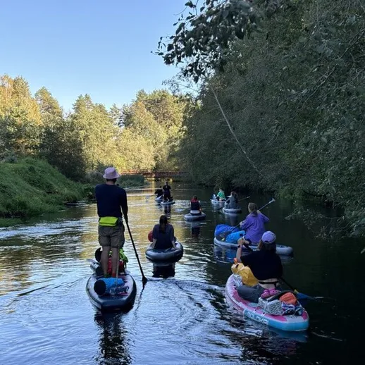 Группа людей на водных лыжах плывёт по спокойной реке в осенний день