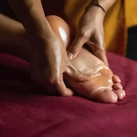 Массаж стопы на мягком покрытии с использованием масла, вечернее время, расслабляющая атмосфера
