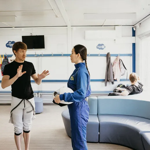 Обсуждение подготовки между тренером и спортсменкой в спортивном зале во время тренировки