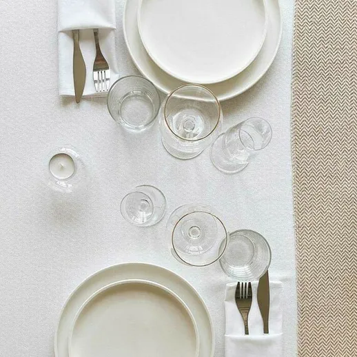 Элегантная сервировка стола на ужин в ресторане с белой скатертью и стеклянной посудой