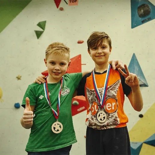 Два мальчика с медалями после соревнований по скалолазанию в спортивном центре на крытой стене