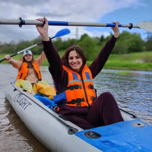 Две женщины катаются на каяке на реке в воскресный день, наслаждаясь природой и хорошей погодой