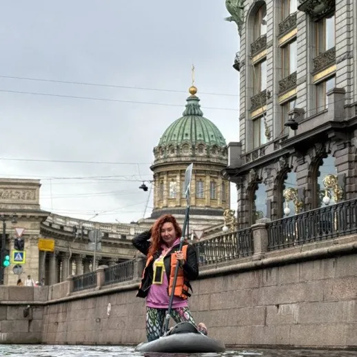 Каякер на канале с историческими зданиями в Санкт-Петербурге в дождливый день