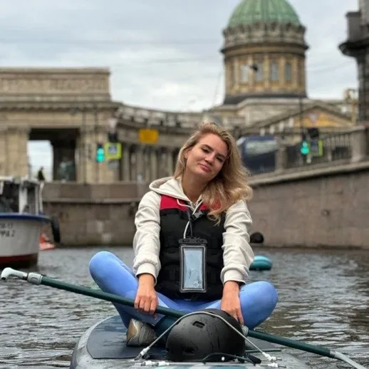 Молодая женщина занимается сап-бордингом на канале в Санкт-Петербурге, наслаждаясь спокойной атмосферой утра