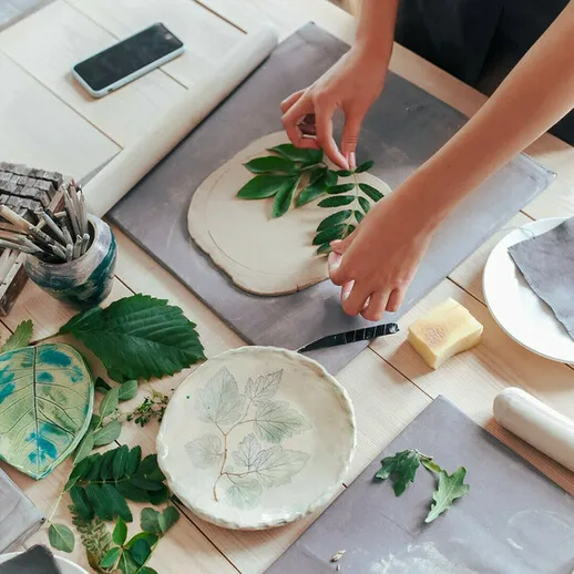 Работа с глиной и листьями на столе в мастерской в солнечный день