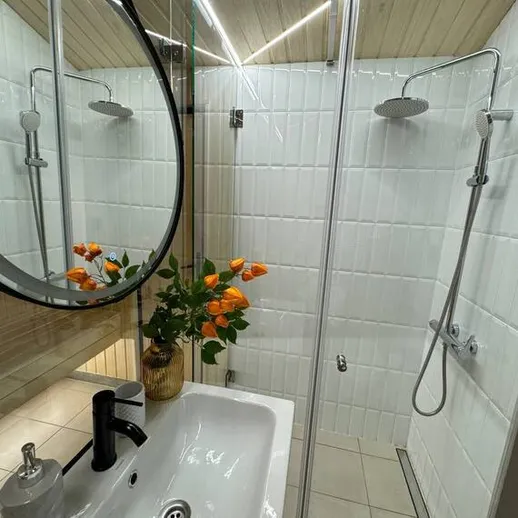 Современная ванная комната с душевой кабиной и оранжевыми цветами, уютное оформление интерьера