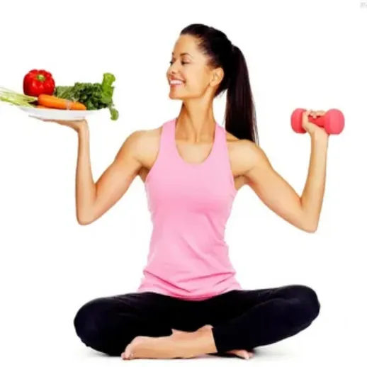 Занятие спортом и правильное питание: женщина в спортивной одежде с гантелей и овощами
