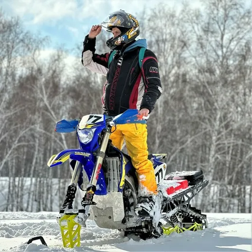 Мотоциклист на снегоходе в зимнем лесу под ярким солнцем