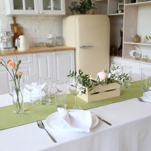 Уютный обеденный стол в современном интерьере кухни с цветами и посудой накануне семейного ужина