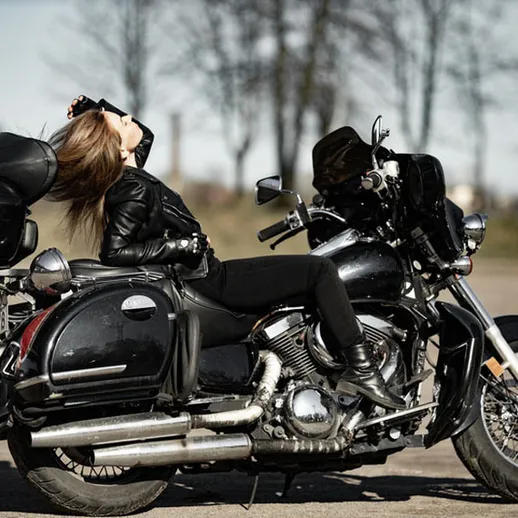 Молодая женщина в кожаной куртке отдыхает на мотоцикле в атмосфере свободы на открытом воздухе в солнечный день