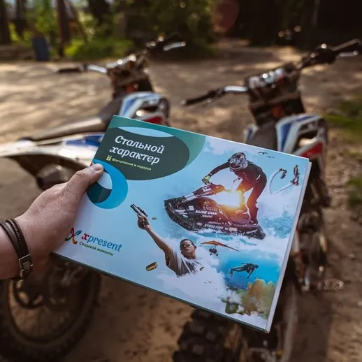 Человек держит рекламный буклет о водных видах спорта рядом с мотоциклами на природе в солнечный день