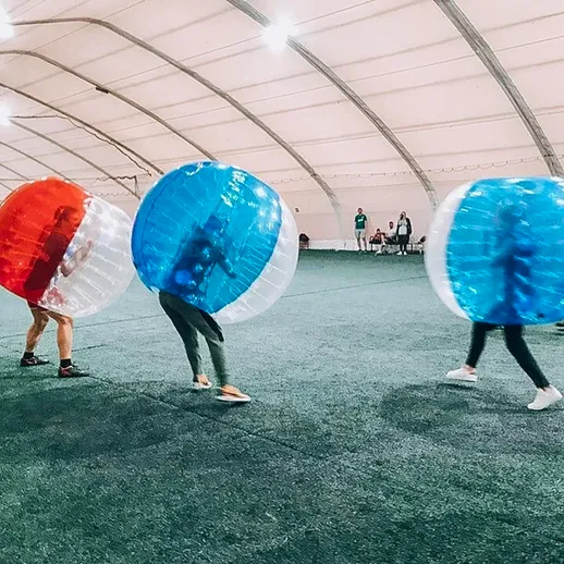 Участники забавной игры в бамперные мячи на спортивной площадке в зимний период