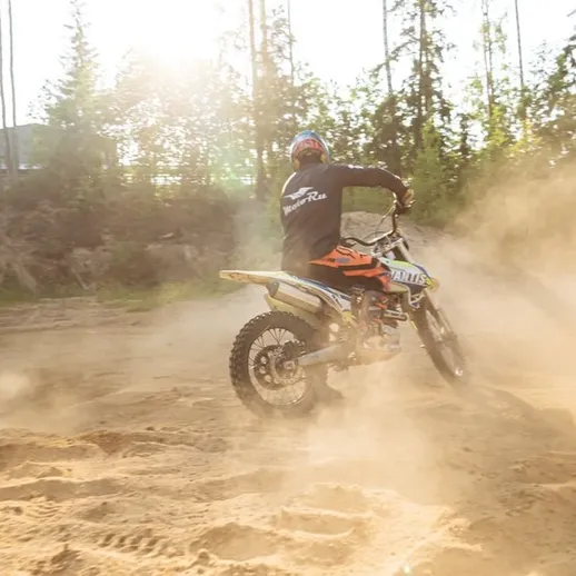 Соревнования по мотокроссу на песчаном треке в лесу, всевозможные маневры и подъемы в солнечный день