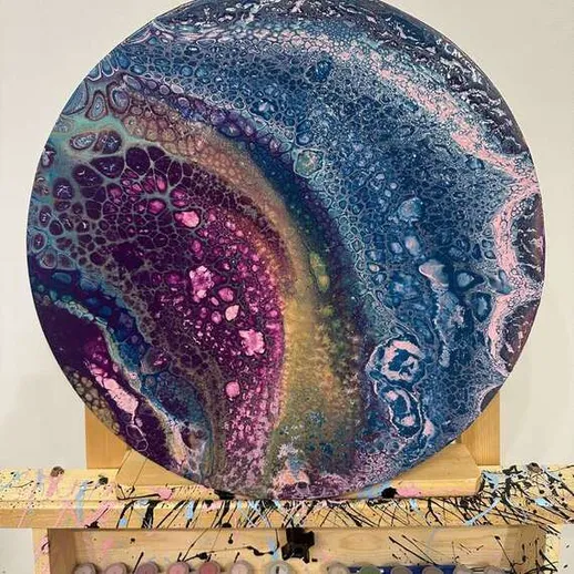 Абстрактная картина с яркими цветами и текстурой, стоящая на мольберте в студии художника