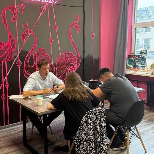 Учащиеся занимаются в уютной комнате на курсе, окруженные яркими фламинго