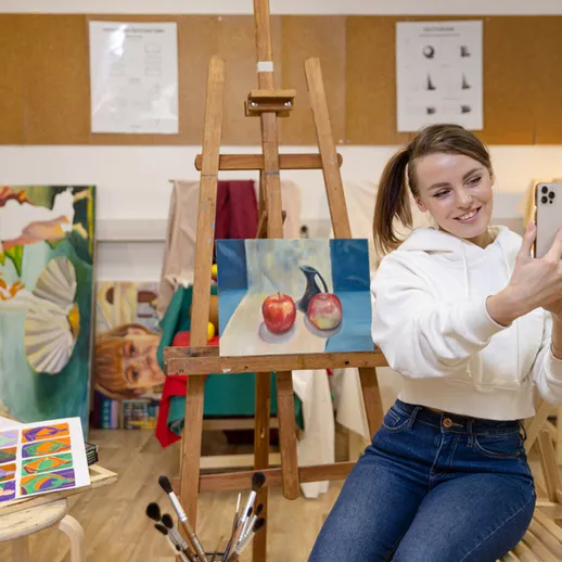 М年轻ая женщина делает селфи на фоне картин в художественной студии