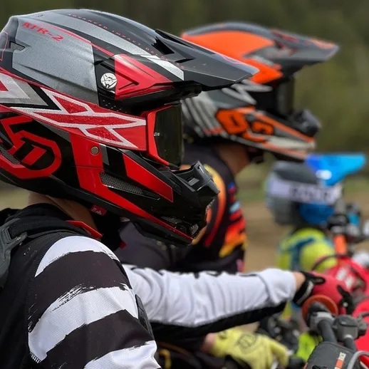 Мотоциклисты в защитных шлемах готовятся к заезду на соревнованиях на природе в солнечный день