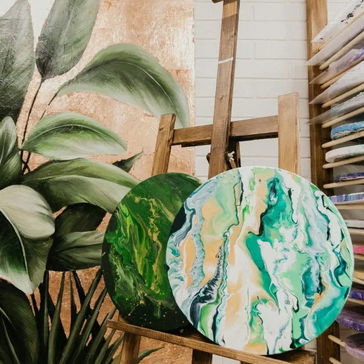 Яркие абстрактные картины на мольберте в художественной мастерской с зелеными акцентами