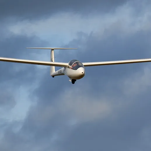 Летящий планер в облаках над живописным ландшафтом в ясный день