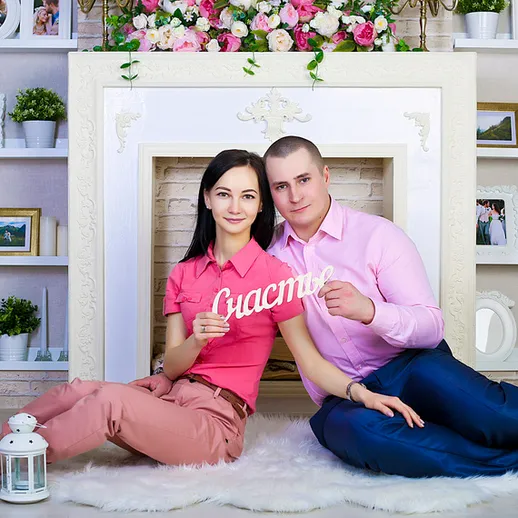 Молодая пара с табличкой «Счастье» на фоне уютного интерьера в светлой комнате