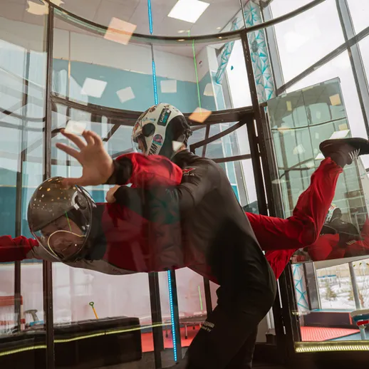 Люди летают в аэротрубе в помещении спортивного центра зимой