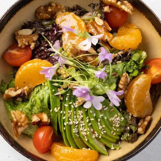 Вегетарианский салат с авокадо, мандаринами и орехами, украшенный цветами, время обеда