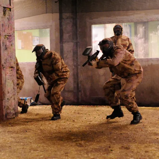 Группа игроков в пейнтбол ведет игру в закрытом помещении с укрытиями и препятствиями