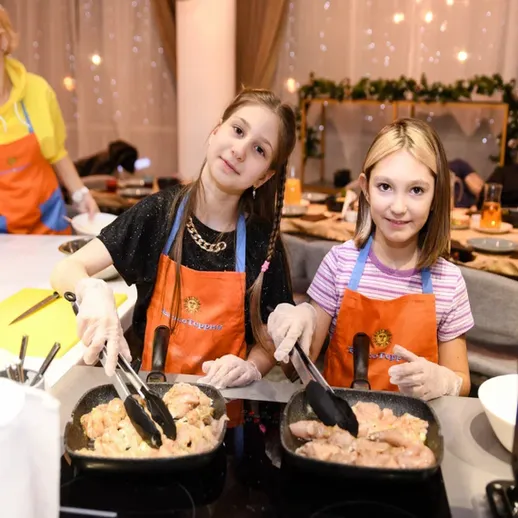 Две девочки готовят на кухне, участник кулинарного мастер-класса с дружелюбной атмосферой