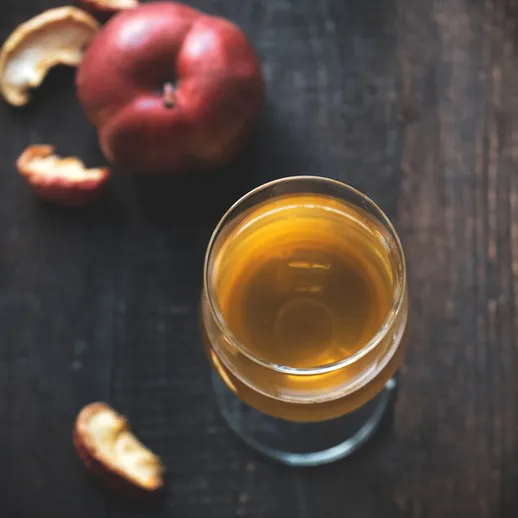 Напиток из яблок на деревянной поверхности с яблоком и коркой рядом