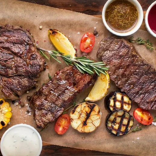 Ассорти из стейков на гриле с овощами и соусами в уютном ресторане, вечернее время, атмосфера уюта и наслаждения