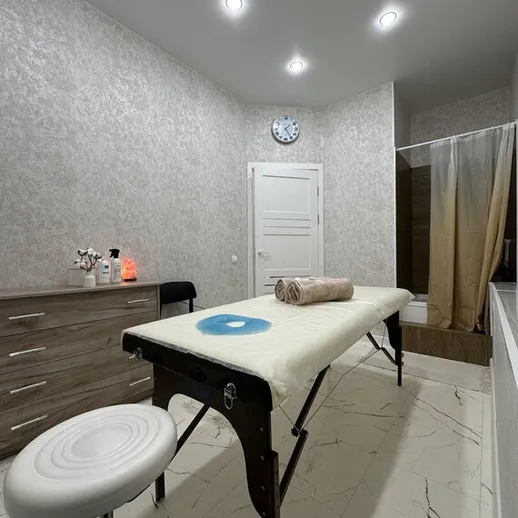 Просторный массажный кабинет с белоснежным столом и современным декором в расслабляющей атмосфере