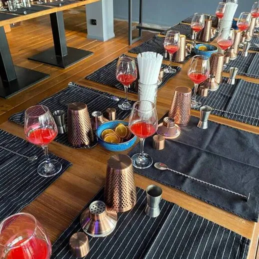 Стол, накрытый для коктейльного мастер-класса в современном баре, украшенный стильными аксессуарами и красивыми напитками