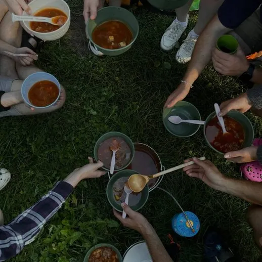 Групповая трапеза на природе с ухой и свежими овощами в летний день