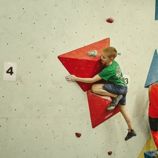 Мальчик занимается скалолазанием на искусственной стене в спортзале в выходной день