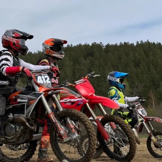 Дети на мотоциклах готовятся к гонке на мотокроссовой трассе в живописной местности в ясный день