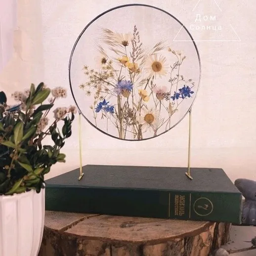 Нежный букет из сухих цветов на столе среди книг и зелени в уютном интерьере