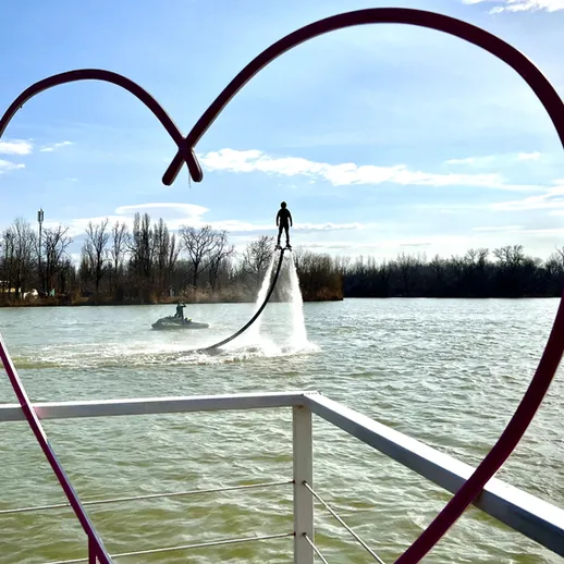 Парень на водном дроне демонстрирует трюки на реке в окружении природы в ясный день