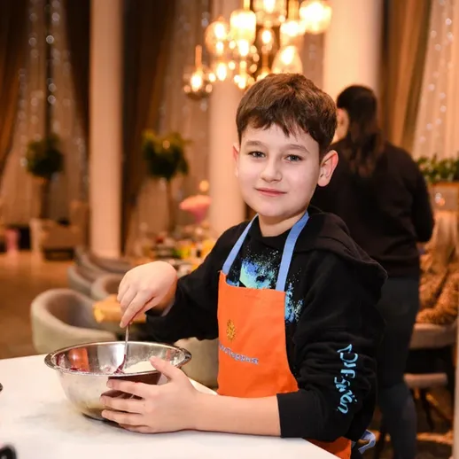 Мальчик готовит в кондитерской студии на мастер-классе в вечернее время