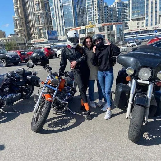 Друзья позируют на мотоциклах на парковке в центре города весной, наслаждаясь временем вместе в теплый солнечный день