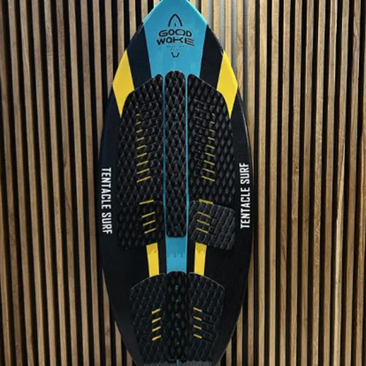 Доска для серфинга с характерным дизайном, выставленная на фоне деревянной стенки в ателье