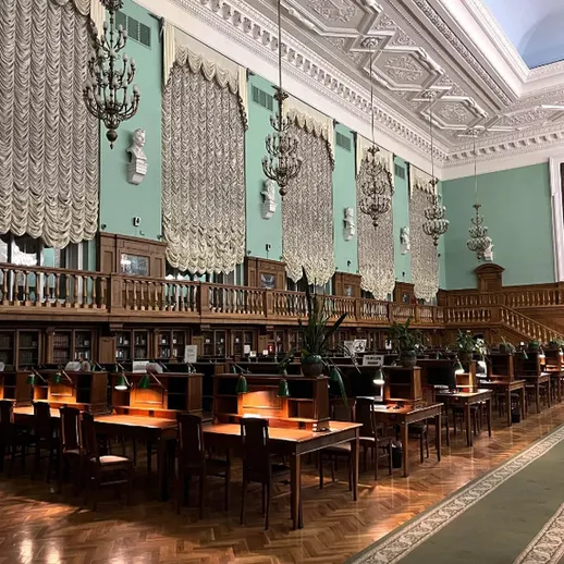 Уютная библиотека с длинными деревянными столами и ярким освещением в часе пик